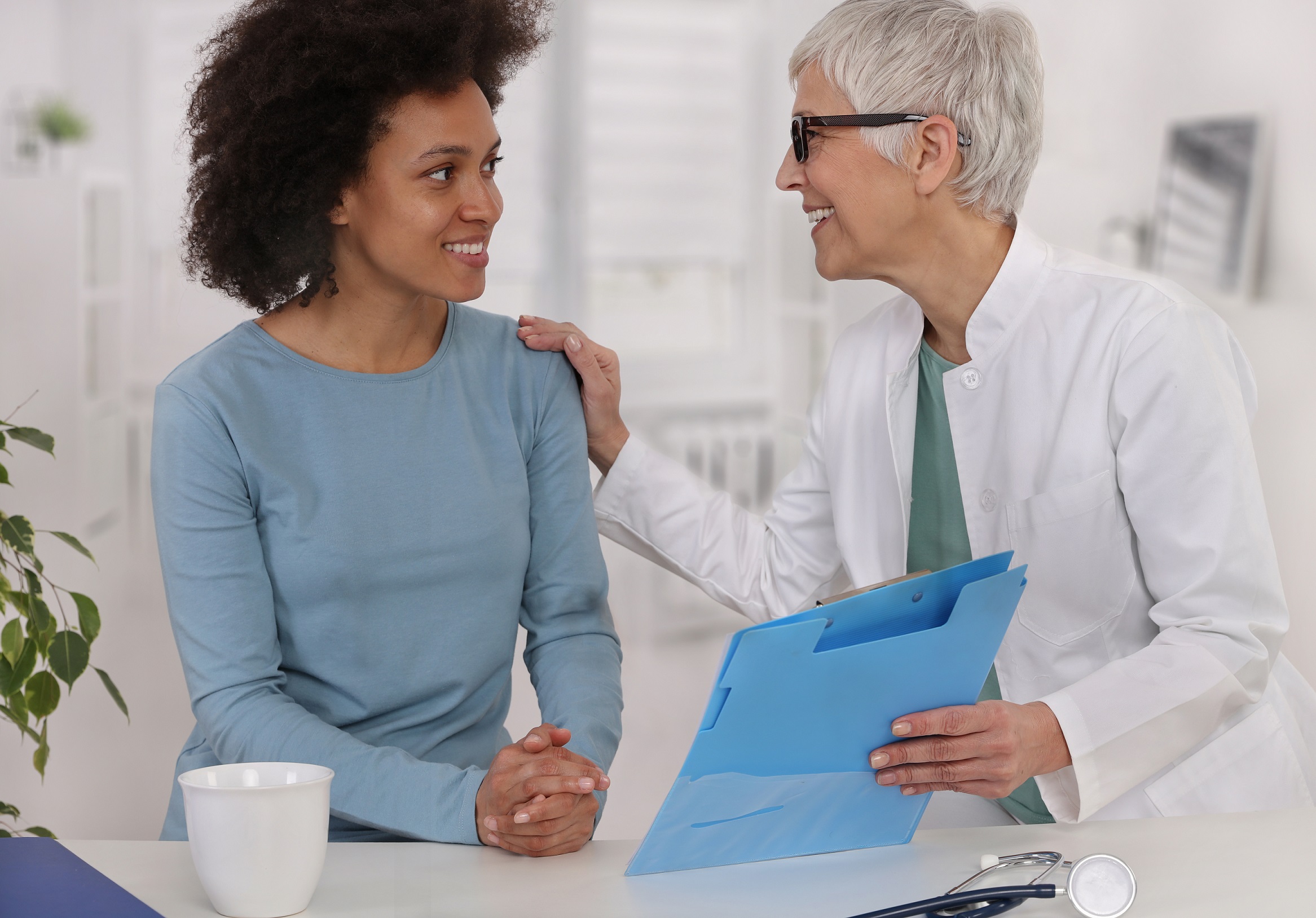 Mature Doctor comforting young Woman Patient